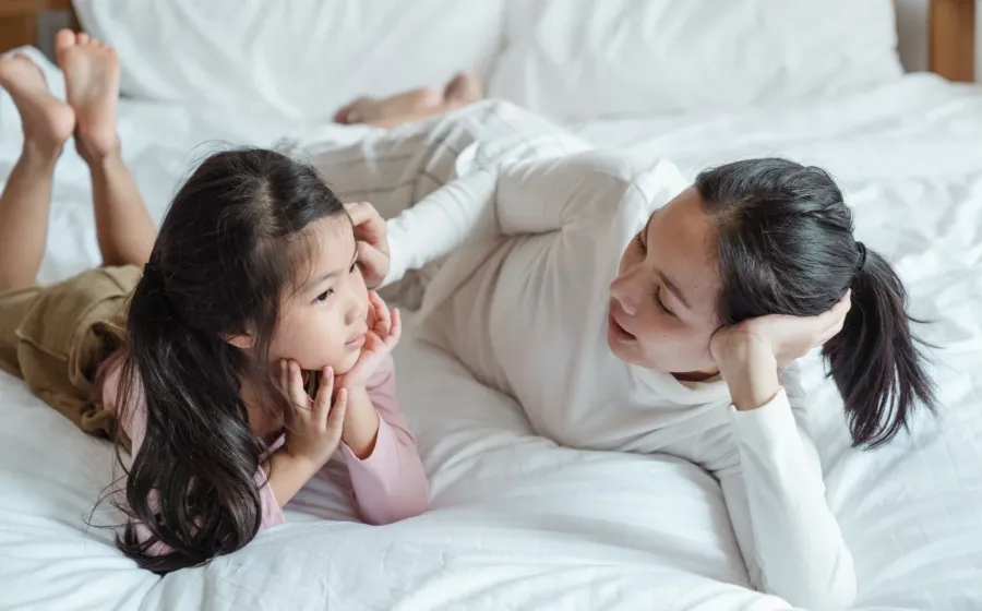 Seorang ibu yang tersenyum sambil mendengarkan penjelasan anaknya untuk mengajari anak berani jujur