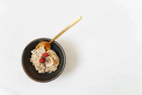Berbagai pilihan makanan sehat untuk penderita maag seperti oatmeal dan pisang di atas meja kayu