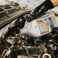 Mekanik menuangkan cairan pelumas untuk menunjukkan perbedaan oli mineral dan sintetik pada mesin mobil
