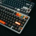 Rekomendasi keyboard mekanik terbaik tipe hot-swappable dengan lampu RGB menyala di atas meja kerja kayu
