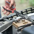 Mekanik sedang memeriksa tanda aki motor lemah menggunakan voltmeter di bengkel