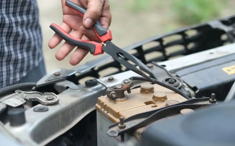 Mekanik sedang memeriksa tanda aki motor lemah menggunakan voltmeter di bengkel